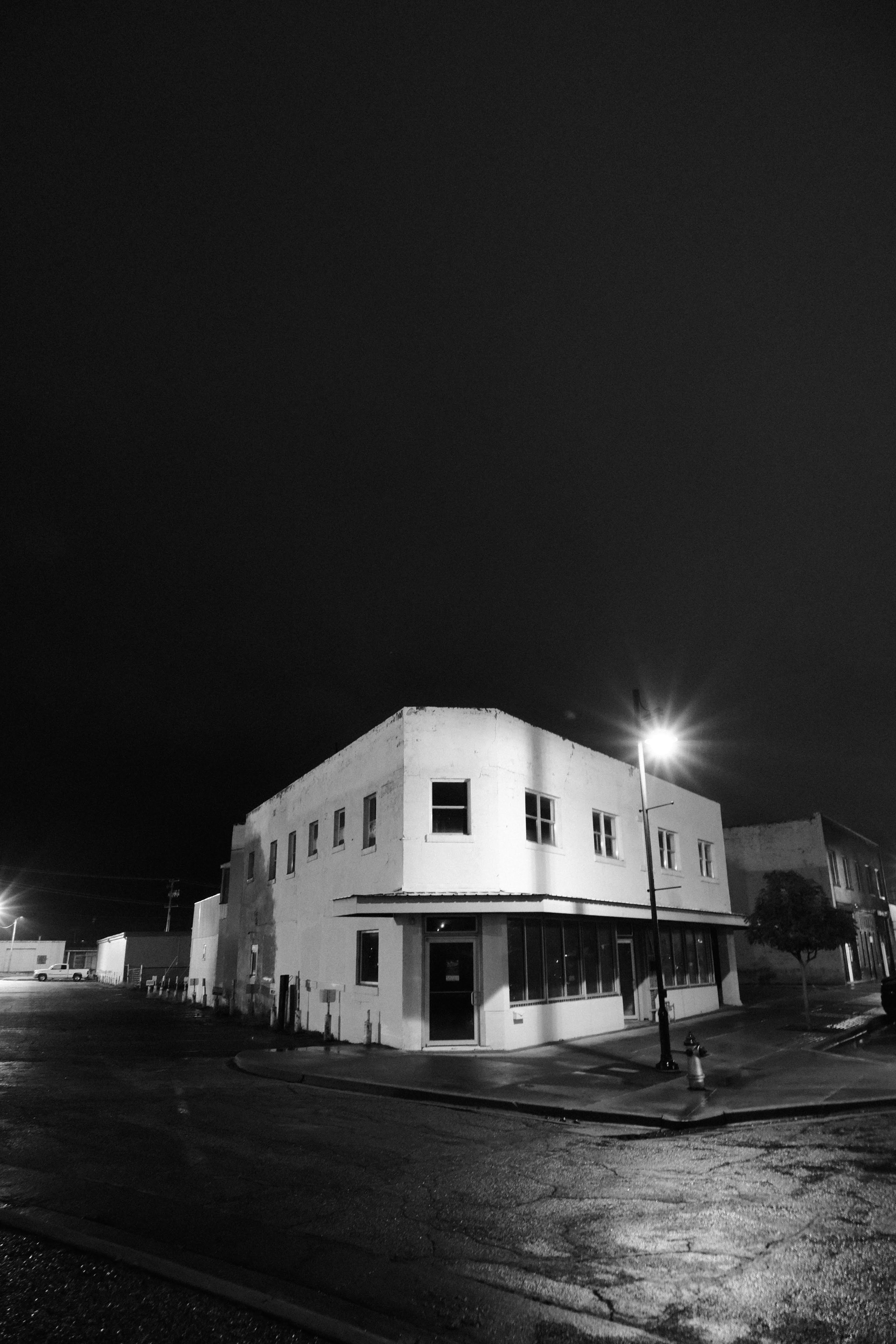The corner building at night, streetlight overhead, windows dark