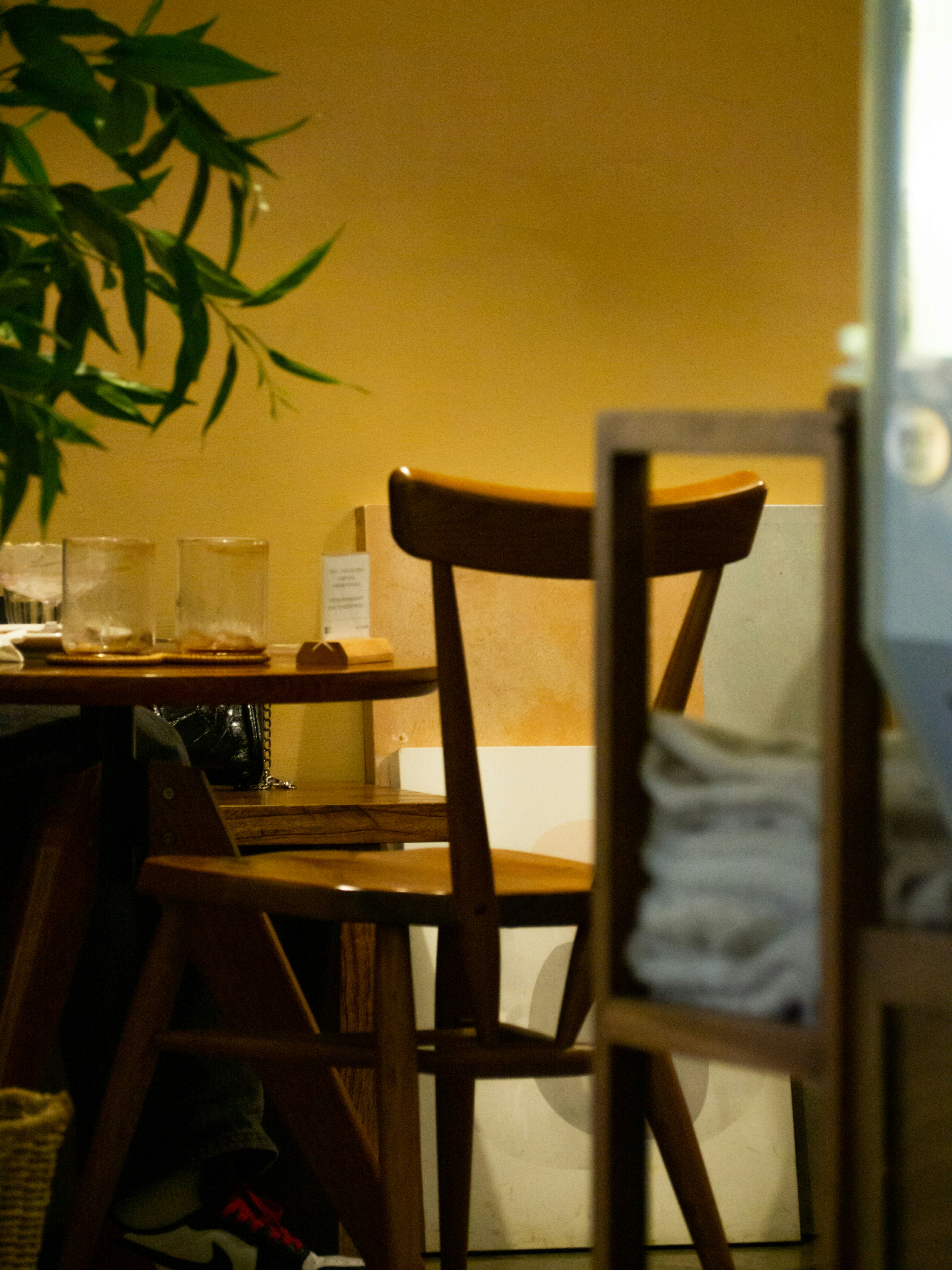 A wooden chair and table inside the diner, warm light, plant in the corner